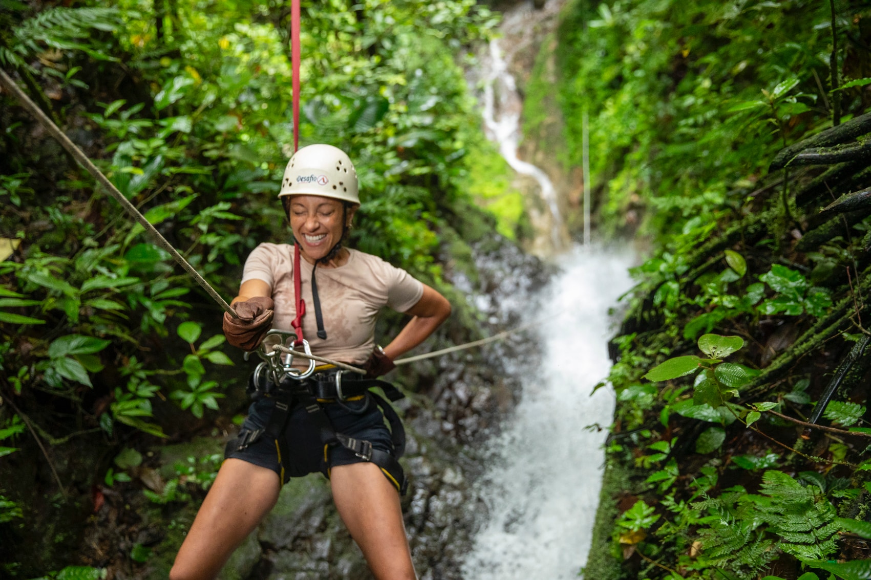 costa rica waterfall rappelling a happy female traveller rappels down a Costa Rican waterfall