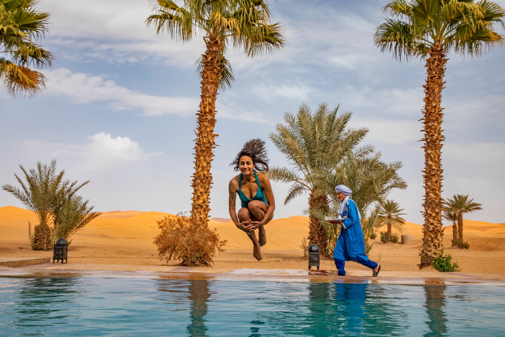 morocco oasis pool jump a happy female traveller cannonballs into a desert oasis pool