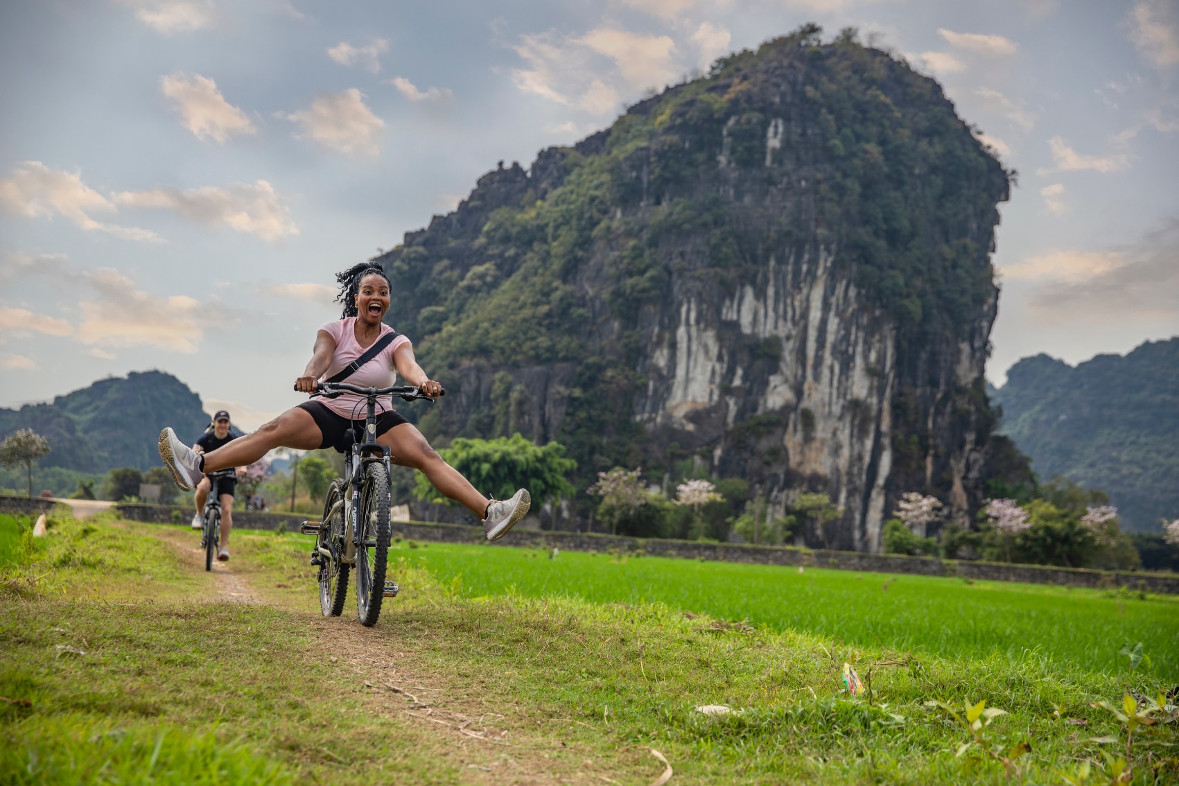 Vietnam bicycle tour a smiling female traveller bikes past limestone karsts in Vietnam